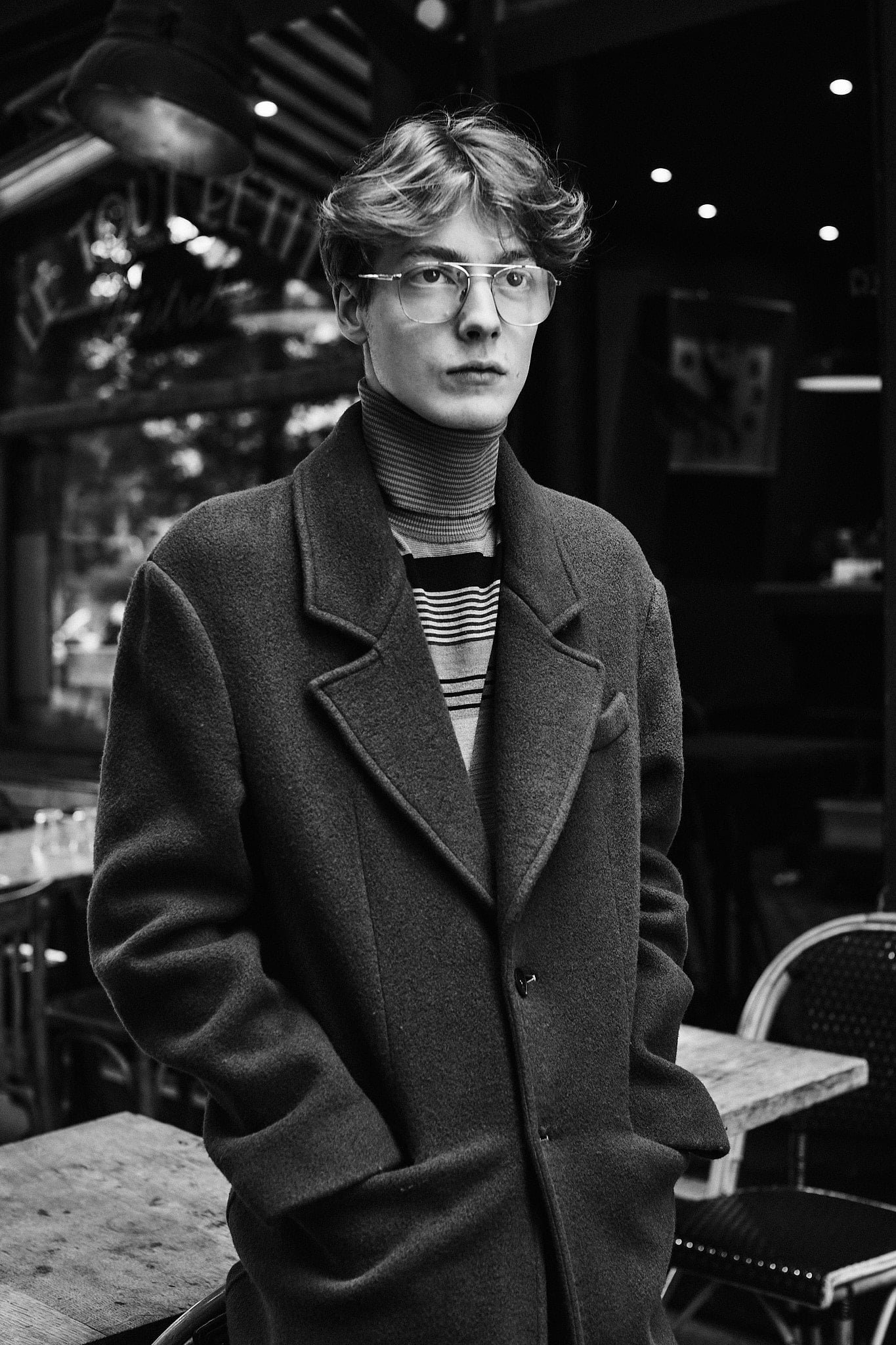 CHARLES DE VILMORIN, directeur artistique de la maison Rochas, ici dans les rues de Paris devant la terrasse d'un café, photo en noir et blanc.